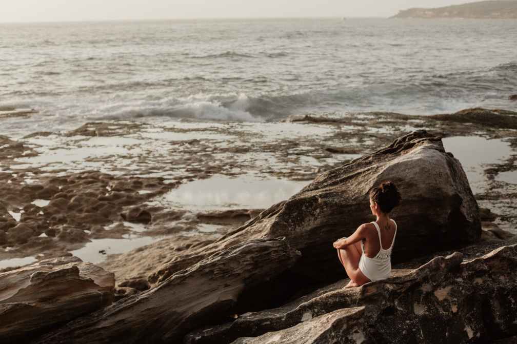 photo of woman sitting on rock