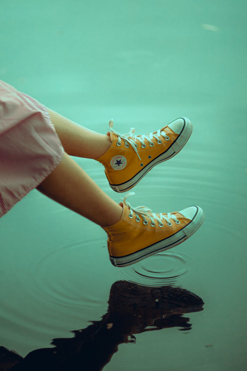 photo of person wearing yellow converse shoes